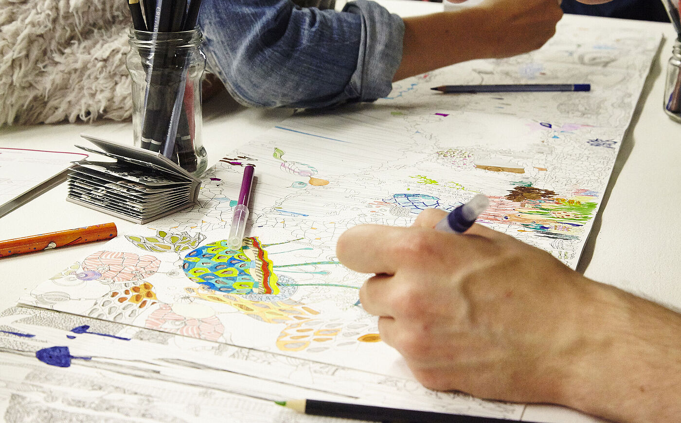 Hände zeichnen bunte Formen auf Papier