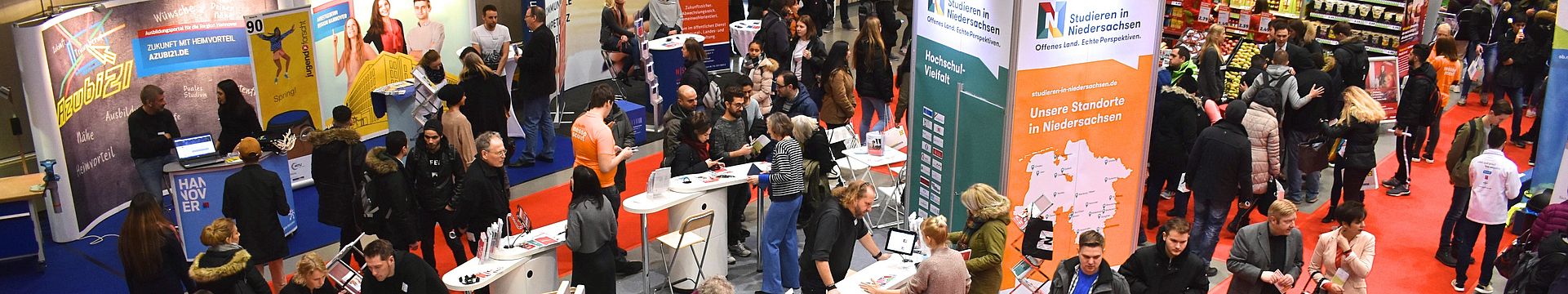 Eine Halle voll mit Ständen und Gästen bei der Messe Beruf und Bildung, im Mittelpunkt der Messestand von Studieren in Niedersachsen, an dem sich viele junge Menschen beraten lassen