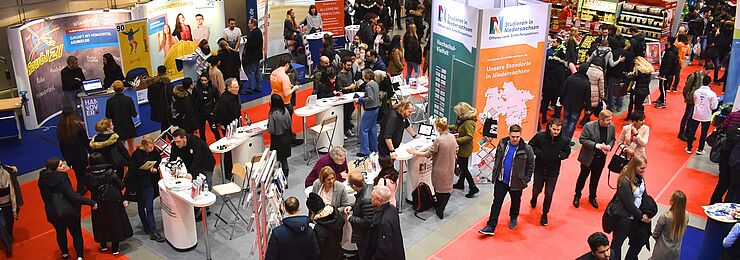 Eine Halle voll mit Ständen und Gästen bei der Messe Beruf und Bildung, im Mittelpunkt der Messestand von Studieren in Niedersachsen, an dem sich viele junge Menschen beraten lassen