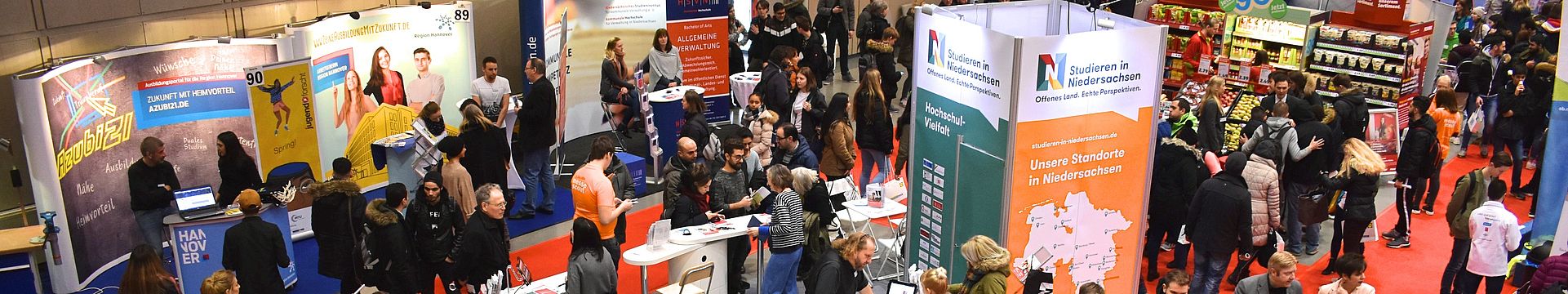 Eine Halle voll mit Ständen und Gästen bei der Messe Beruf und Bildung, im Mittelpunkt der Messestand von Studieren in Niedersachsen, an dem sich viele junge Menschen beraten lassen