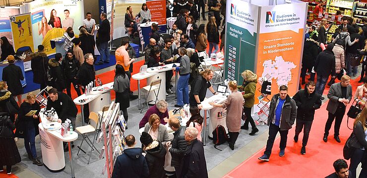 Eine Halle voll mit Ständen und Gästen bei der Messe Beruf und Bildung, im Mittelpunkt der Messestand von Studieren in Niedersachsen, an dem sich viele junge Menschen beraten lassen
