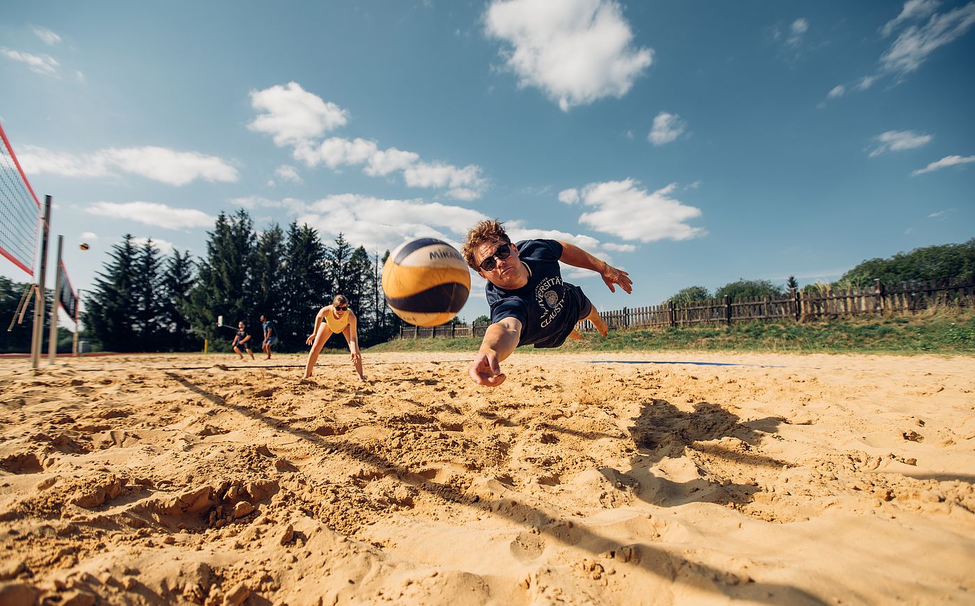 Studierende spielen Beachvolleyball beim Hochschulsport