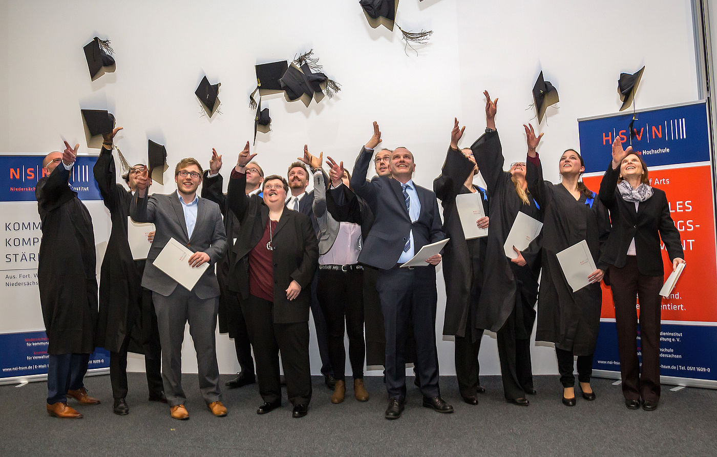 Studierende werfen nach ihrem Studienabschluss an der Kommunalen Hochschule für Verwaltung in Niedersachsen Doktorhüte in die Luft