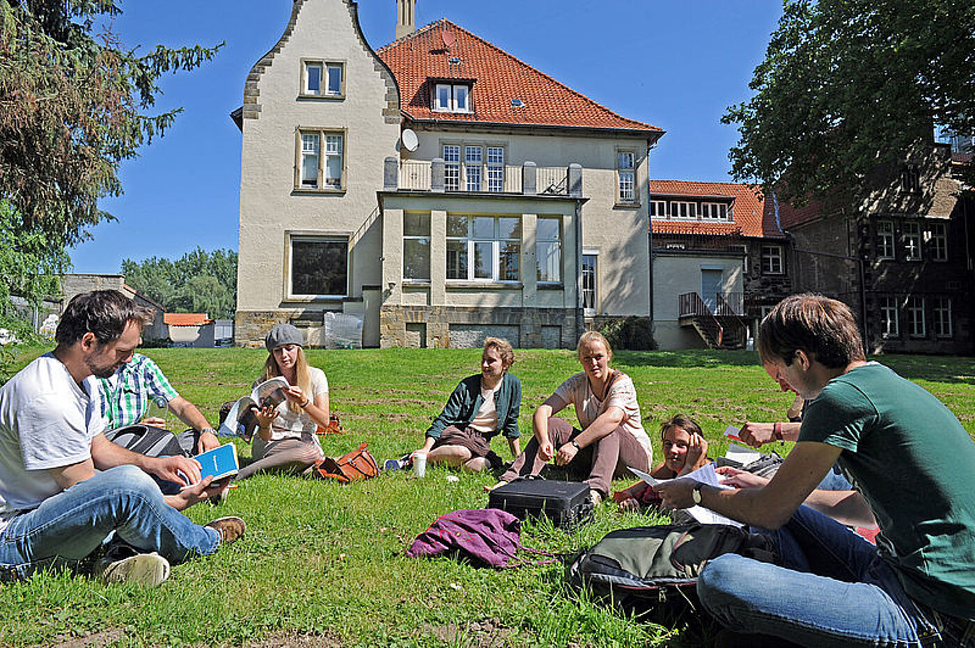 Studierende sitzen auf der Wiese am Kulturcampus der Universität Hildesheim zusammen