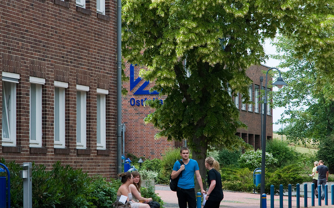 Studierende der Ostfalia HAW sitzen vor dem Hochschulgebäude zusammen