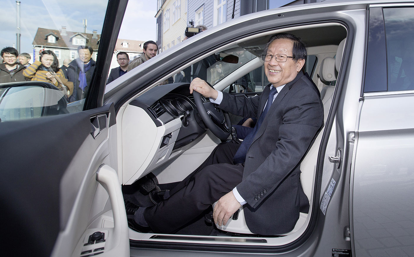 Honorarprofessor Wan Gang am Steuer eines Elektroautos vor dem Hauptgebäude der TU Clausthal