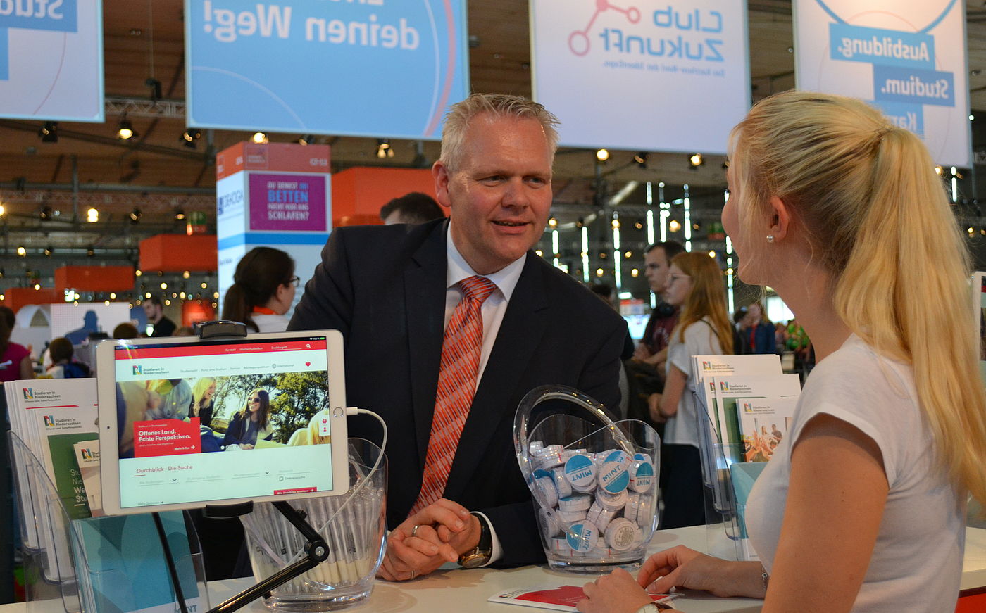 Wissenschaftsminister Björn Thümler unterhält sich mit einer Schülerin am Stand von Studieren in Niedersachsen bei der Messe IdeenExpo
