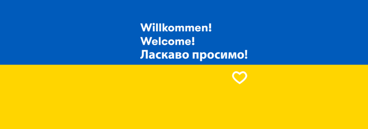 Die Farben der ukrainischen Flagge, oben blau und unten gelb, darauf der Text: Willkommen! Welcome! Ласкаво просимо!